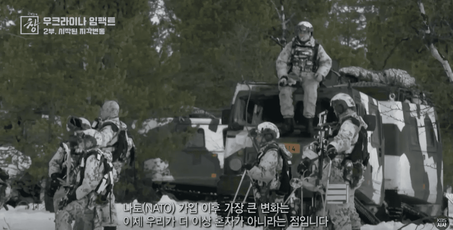 라트비아 내 NATO군 훈련 장면이다. 눈 덮인 겨울 숲에서 완전군장을 착용한 병사들이 군용 차량 위에 올라타 있으며, 자막에 "나토(NATO) 가입 이후 가장 큰 변화는 이제 우리가 더 이상 혼자가 아니라는 점입니다"라고 표시되어 있다. 러-우 전쟁 이후 발트 3국의 NATO군 증강 현황을 보여준다.