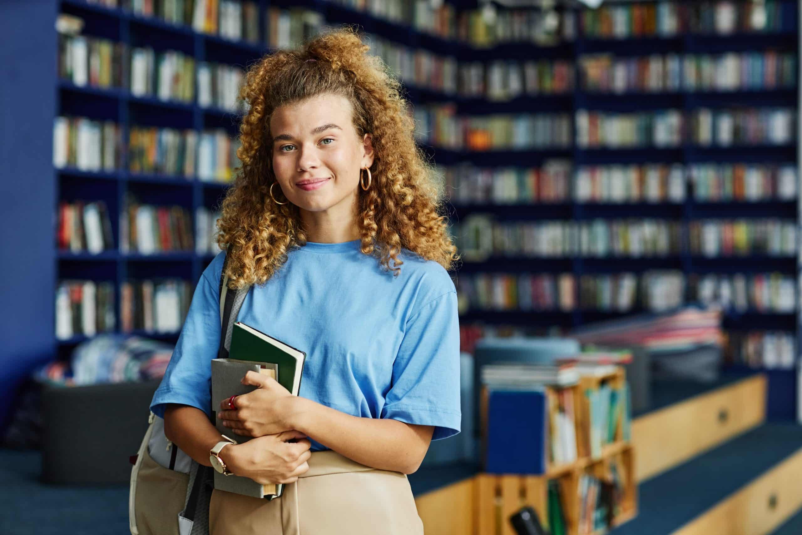 Student in the library with notebooks in hand