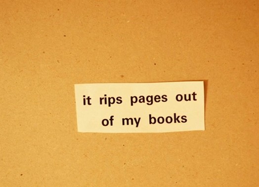 A photo of a piece of paper on an orange table with text: it rips pages out of my book.