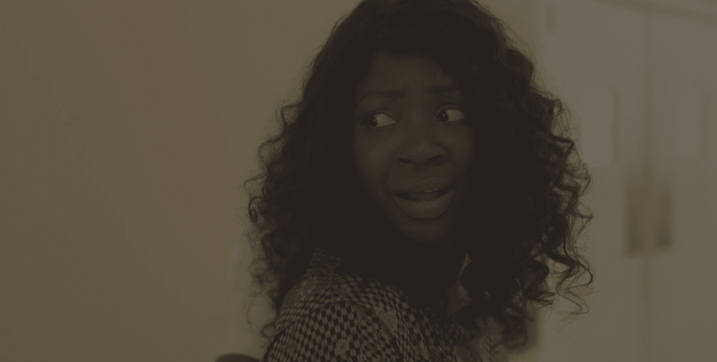 A dark-skinned Black woman, Victoria (Natasha Ofili) with curly, dark hair, looking over her shoulder with concern.