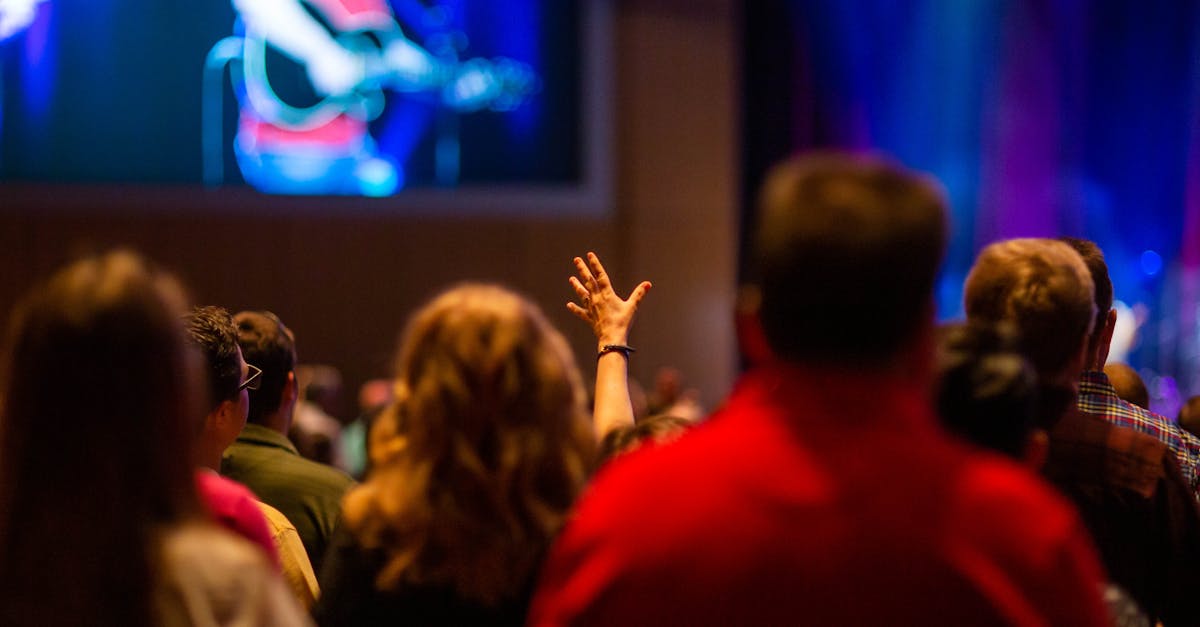 A lively audience enjoying a concert inside a venue, hand raised in excitement.