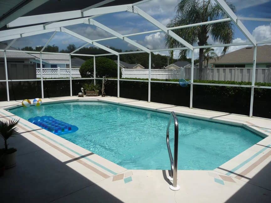 Image of inground pool with accessible entrance. Enclosed by a screen with white frame. Convienet enough to fit in a subdivision.