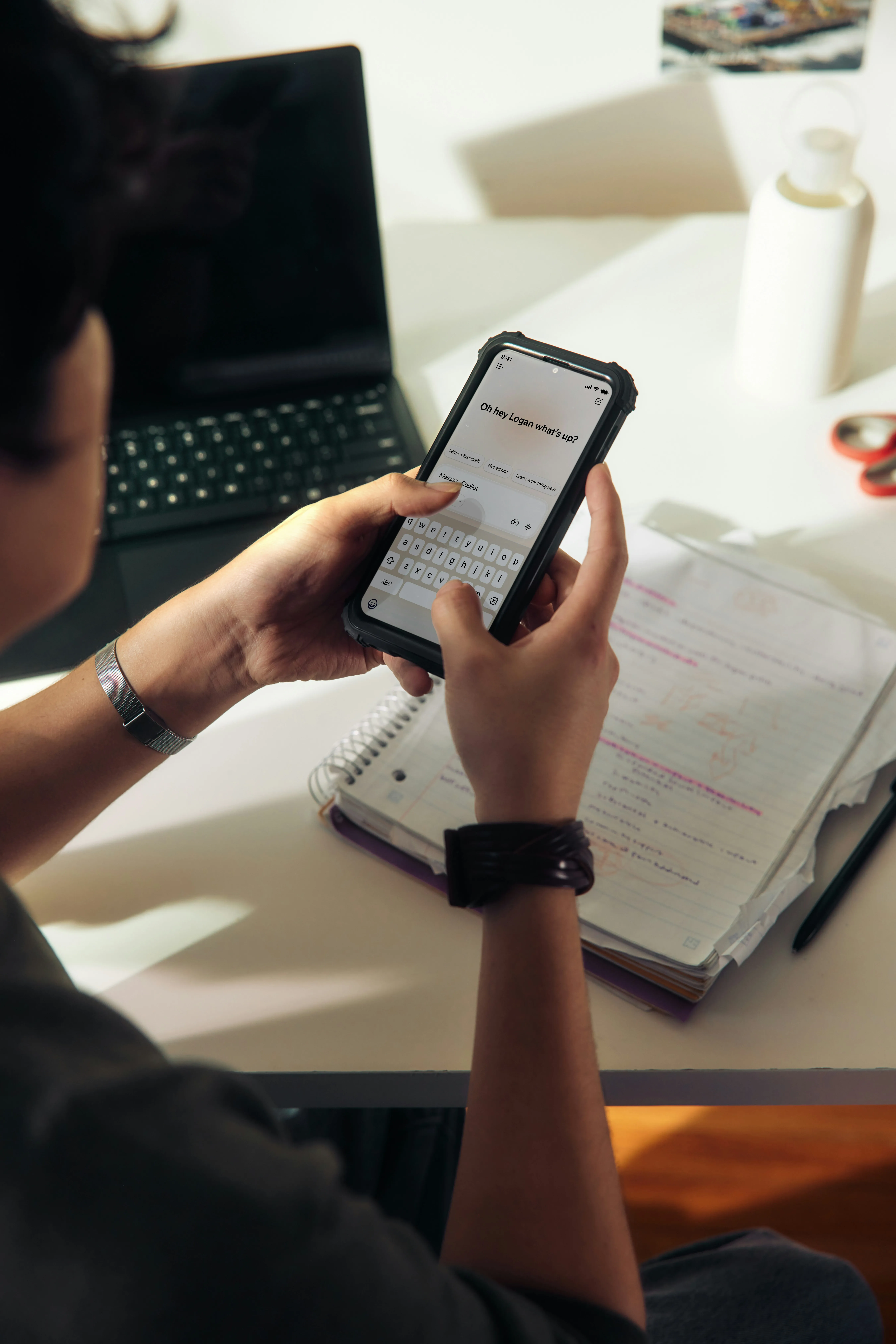 Person using a smartphone over a notebook