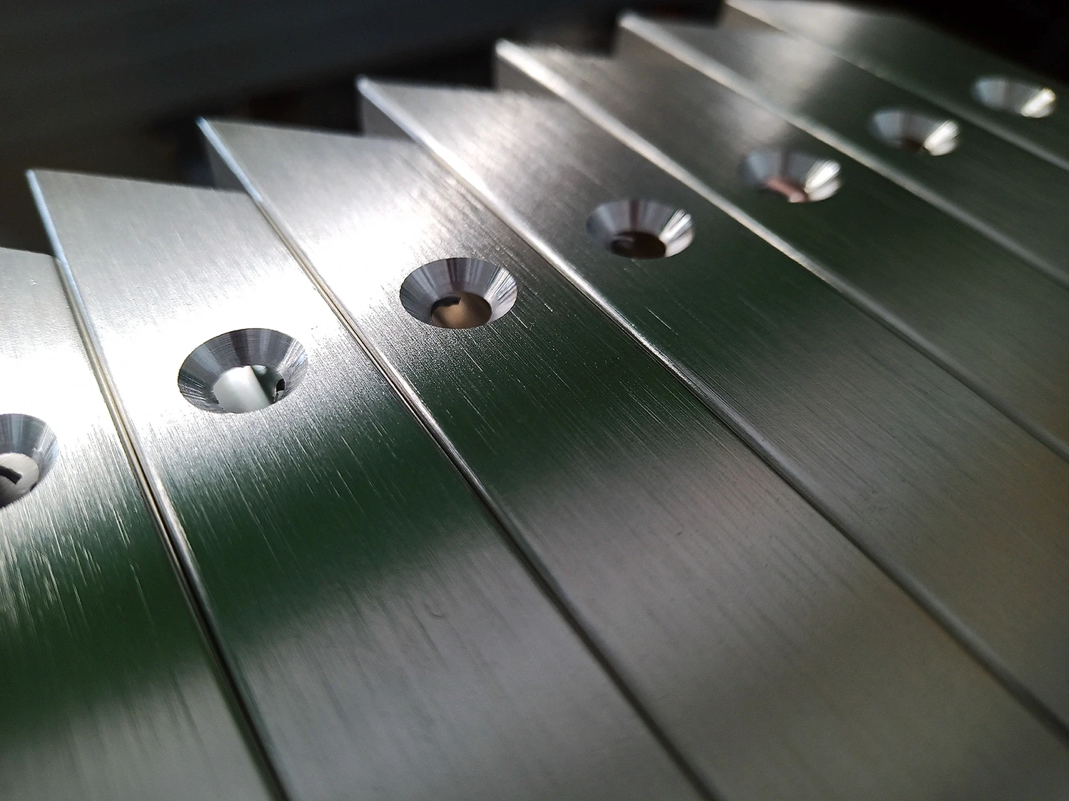 Close-up of precision countersunk holes in brushed metal components.