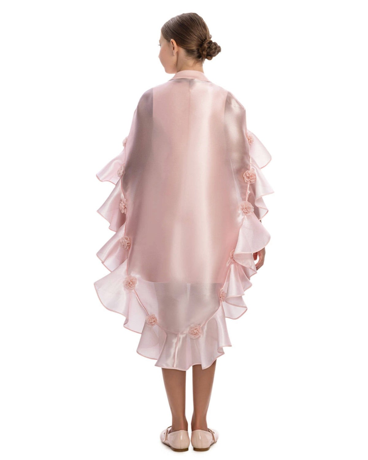 Young girl wearing a pink ruffled dress with floral details on a white background