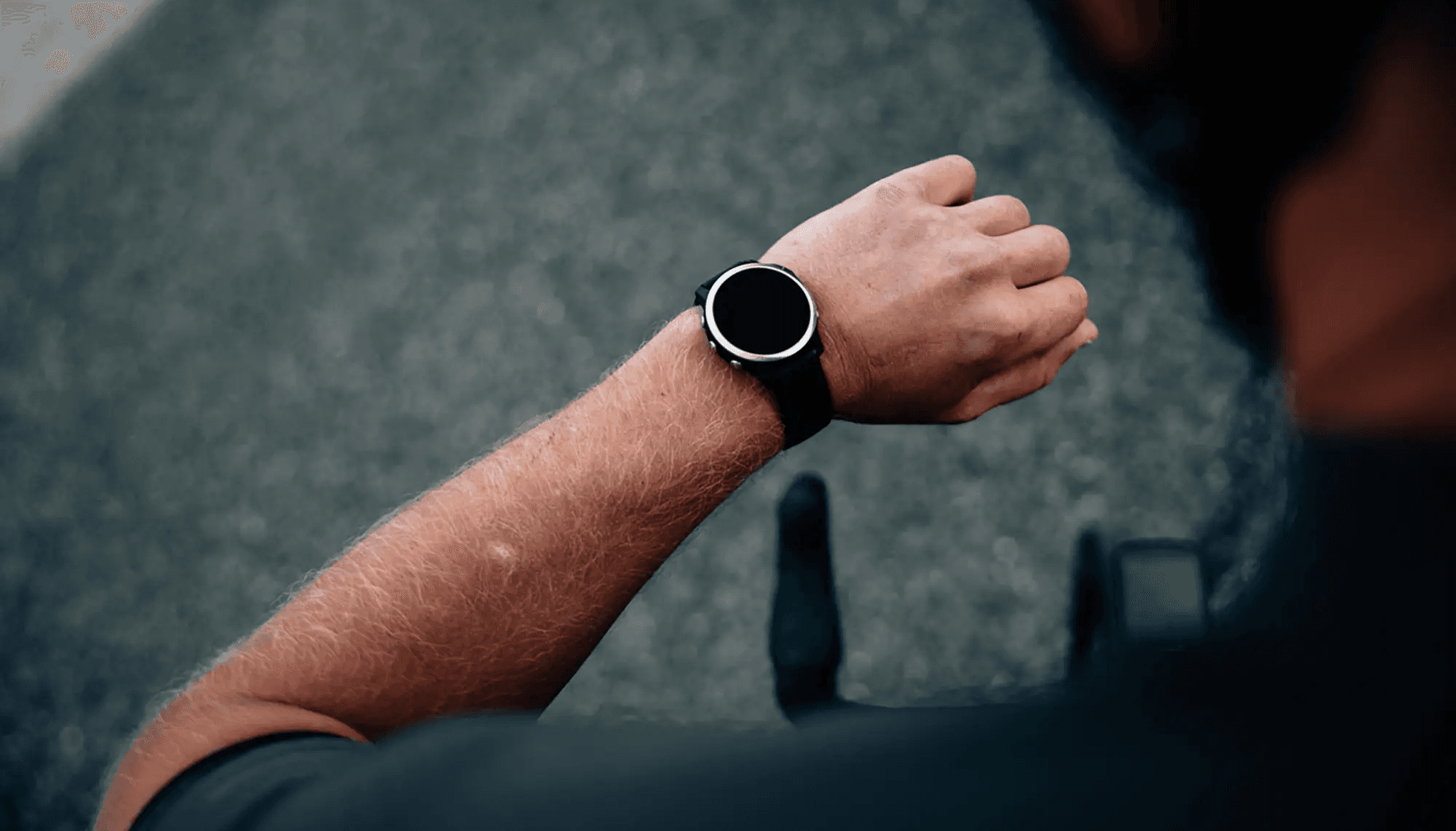 Close-up of a triathlete monitoring their pace and performance data on a GPS watch during an Ironman training session