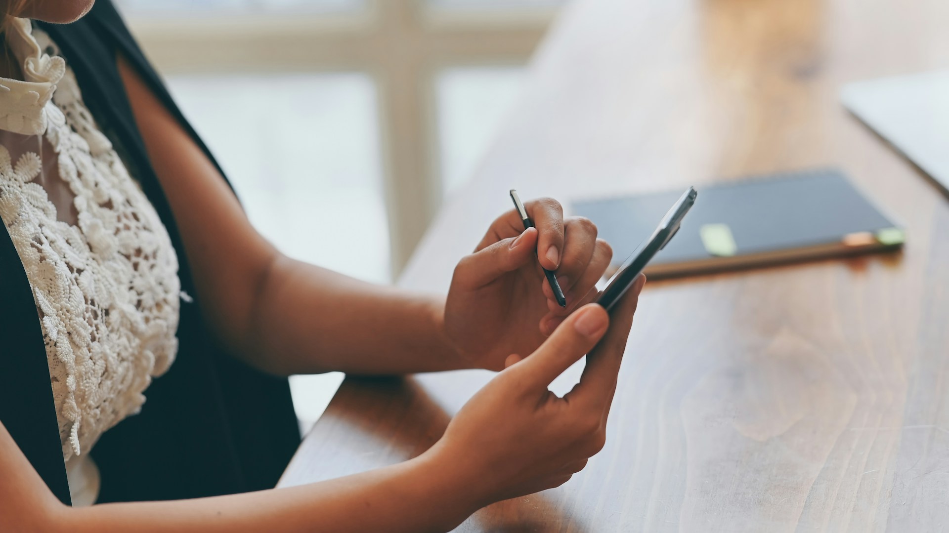 A woman holding a phone and a pen