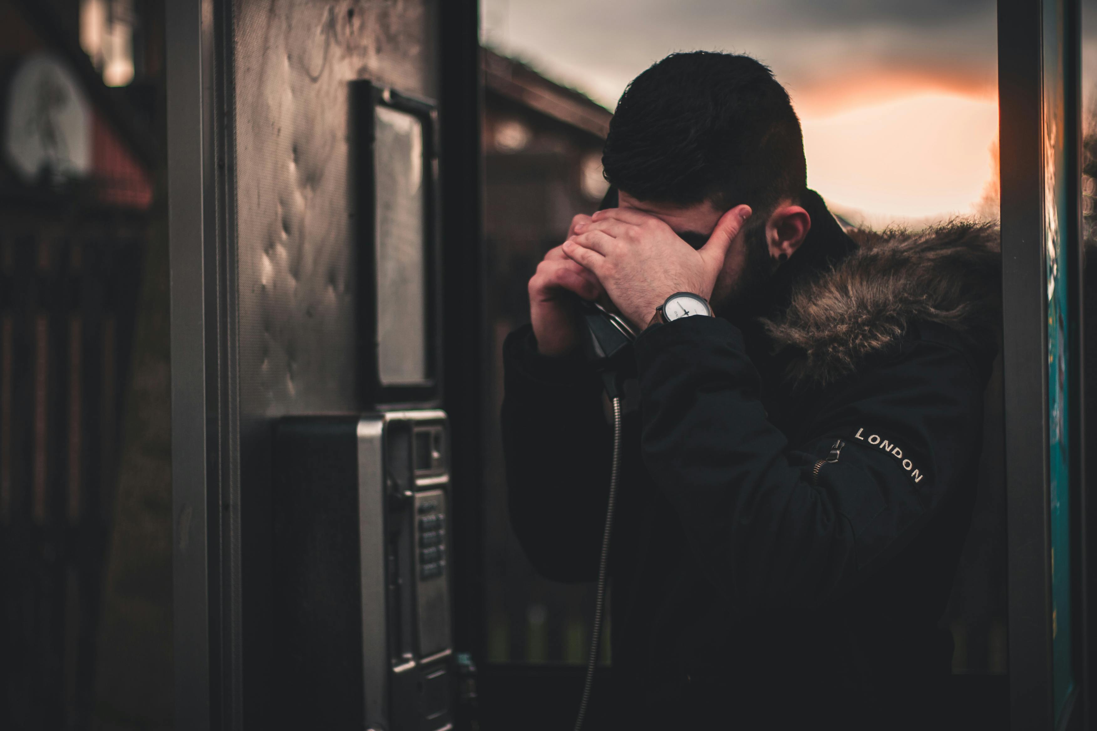 Man Wearing Black Parka Jacket Holding Telephone