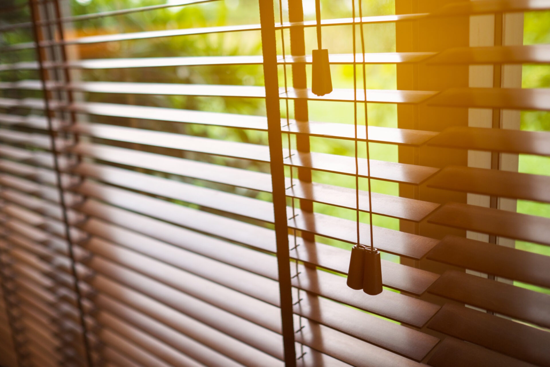 Open faux wooden blinds with sun light peeking through.