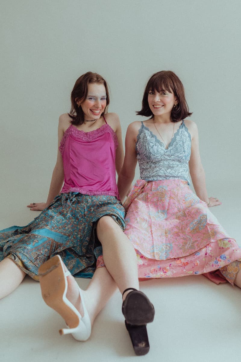 Models sitting side by side, smiling after a creative ethereal photoshoot at Revelator Studio, a natural light studio in Shreveport.