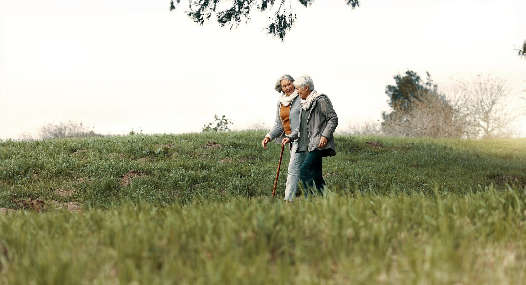 Two older adult women walking through a park