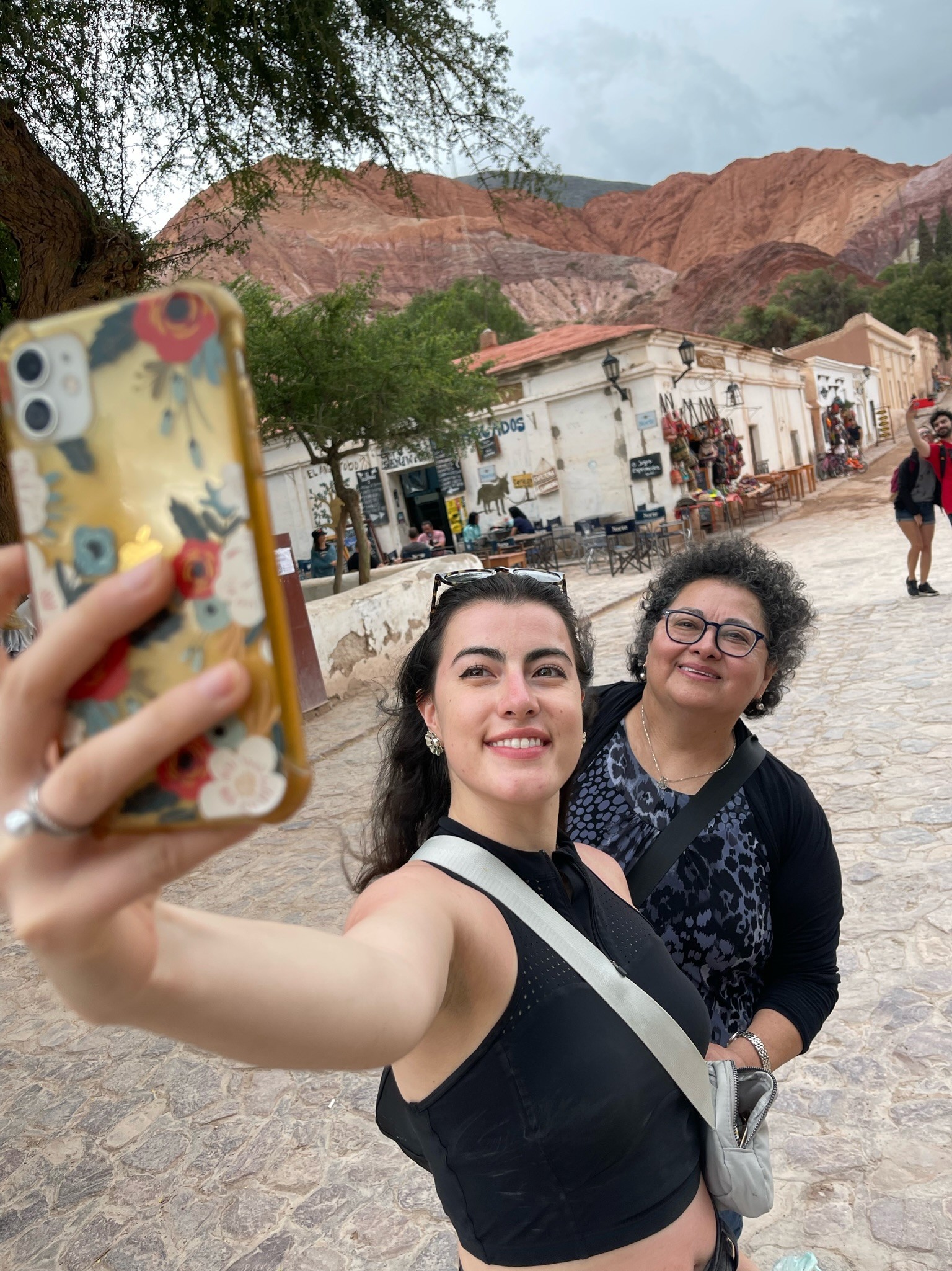 A view from an airplane window shows the aircraft's wing with a golden hue reflecting the setting sun, against a serene backdrop of fluffy clouds and a clear sky.