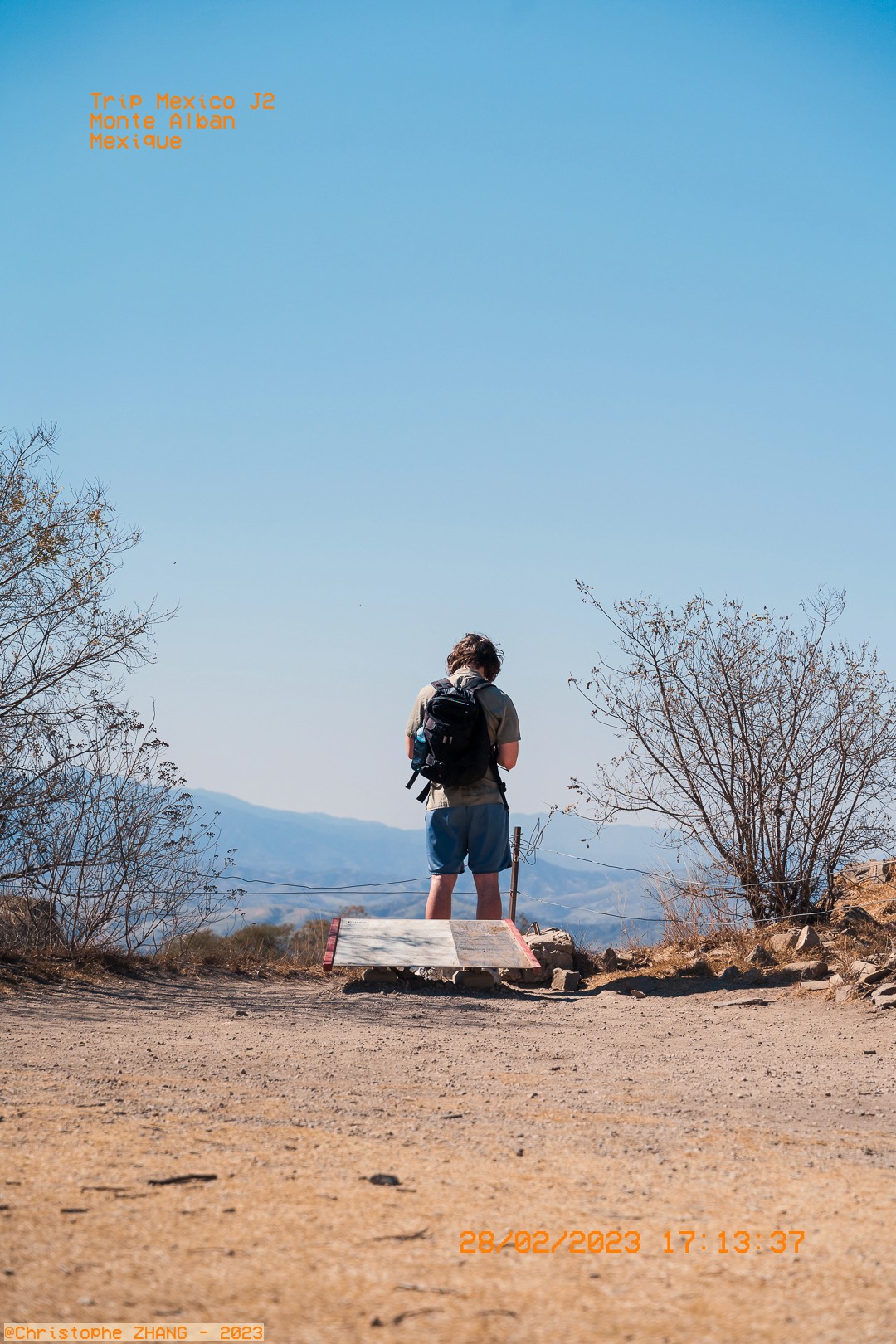 Voyageur consultant un panneau informatif avec vue sur les montagnes.