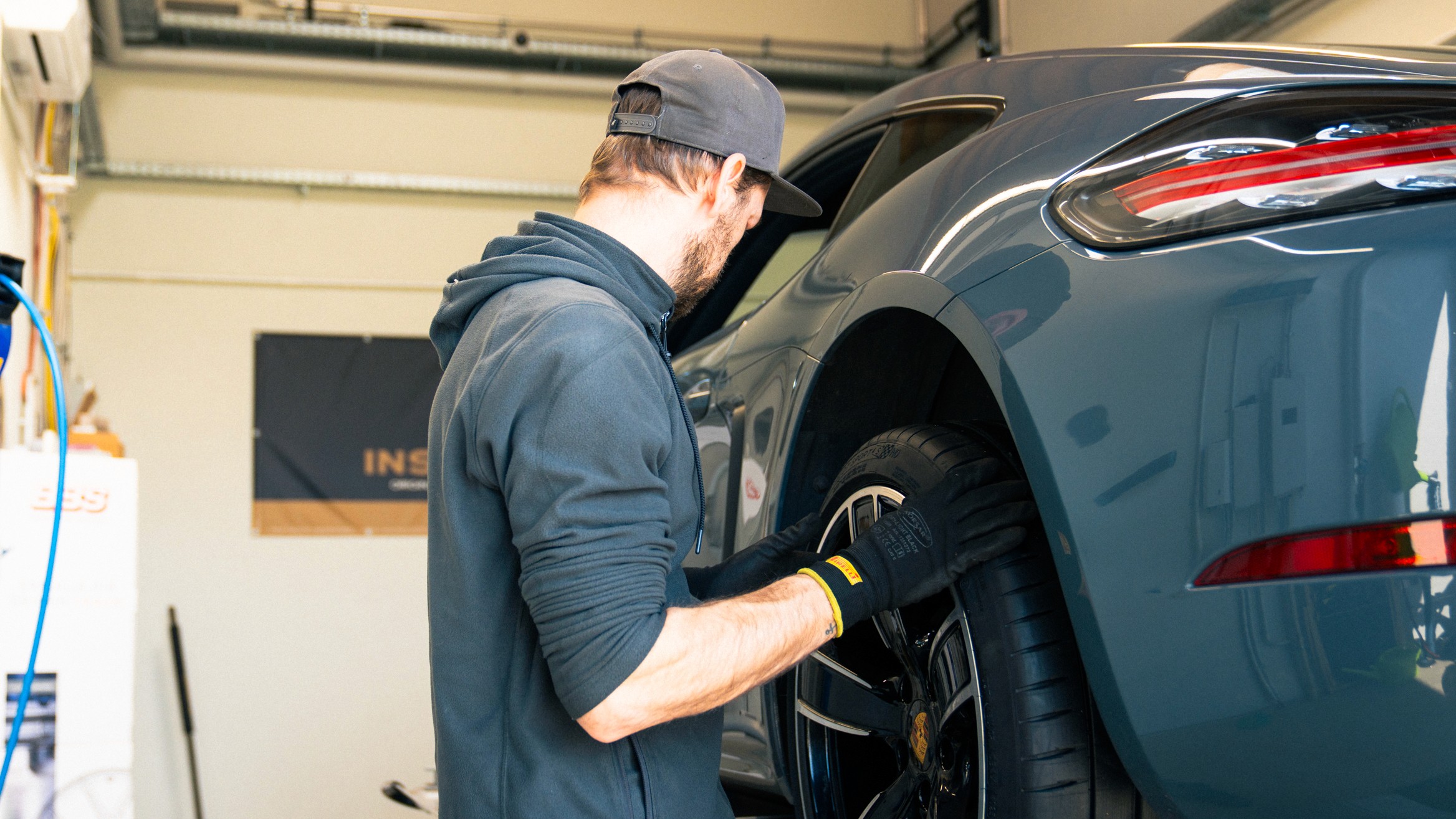 Schwarz-weiß Aufnahme eines Mechanikers bei der Montage eines Reifens an einem Sportwagen – zeigt Fachkompetenz und Präzision bei Insiderfelgen.