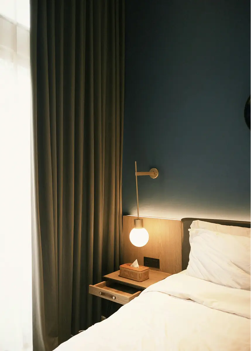 Double bed with bedside lighting and a dark green wall.