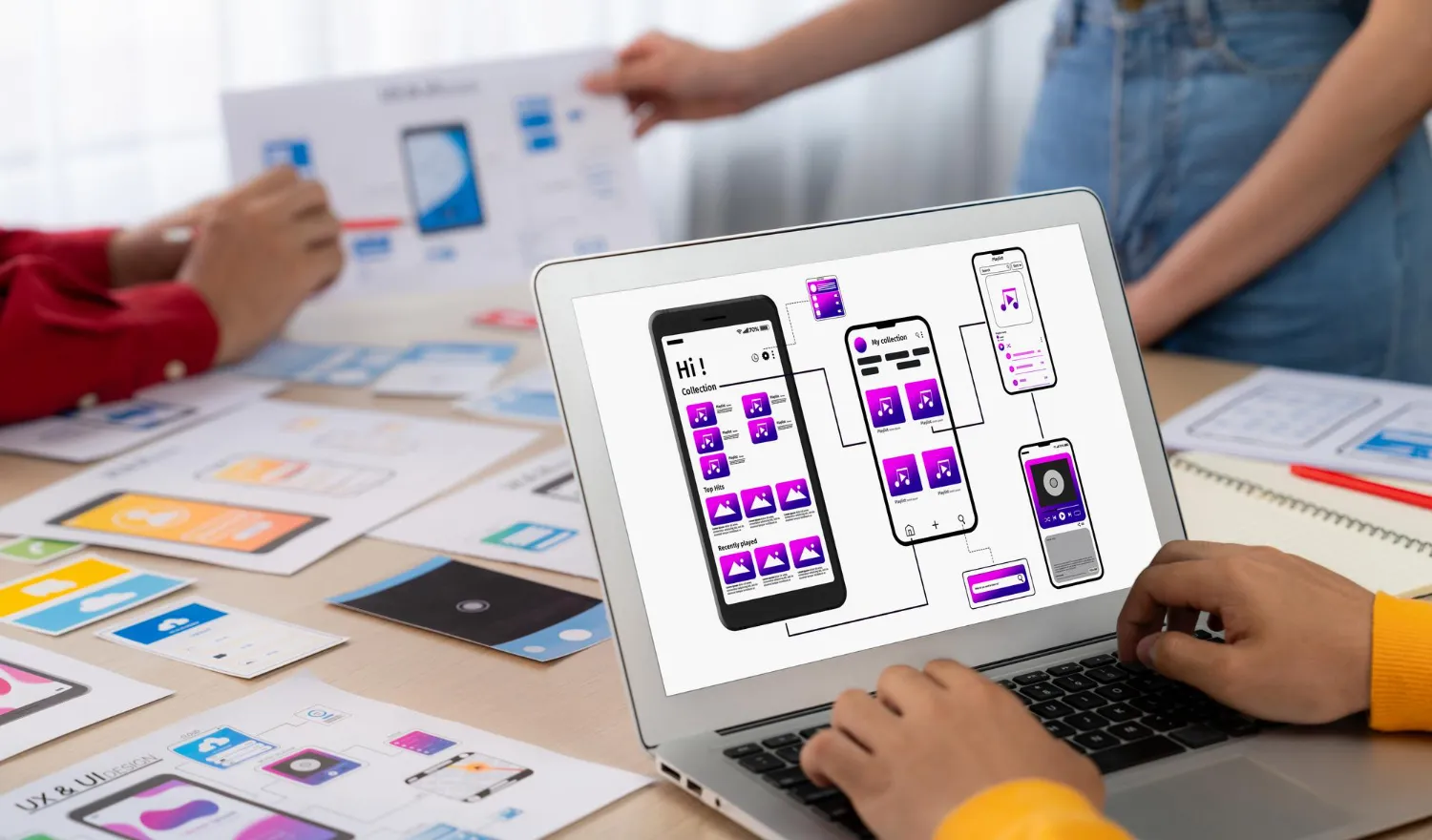 Product team reviewing mobile app wireframes and user flow on a laptop