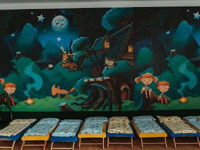 Ložnice pro děti s lehátky a nástěnnou malbou lesa