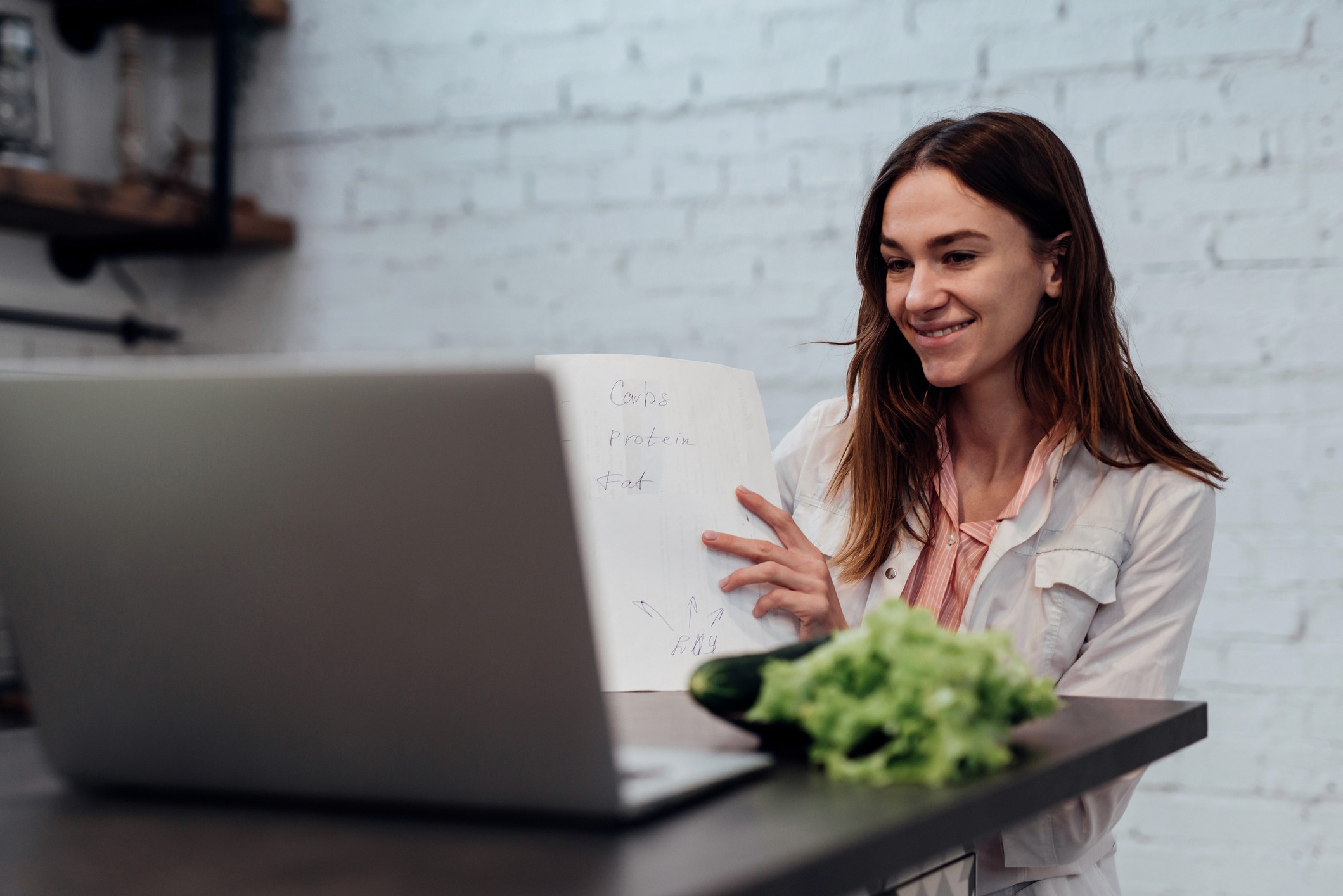 A woman sitting at home using a laptop for a virtual video nutrition appointment