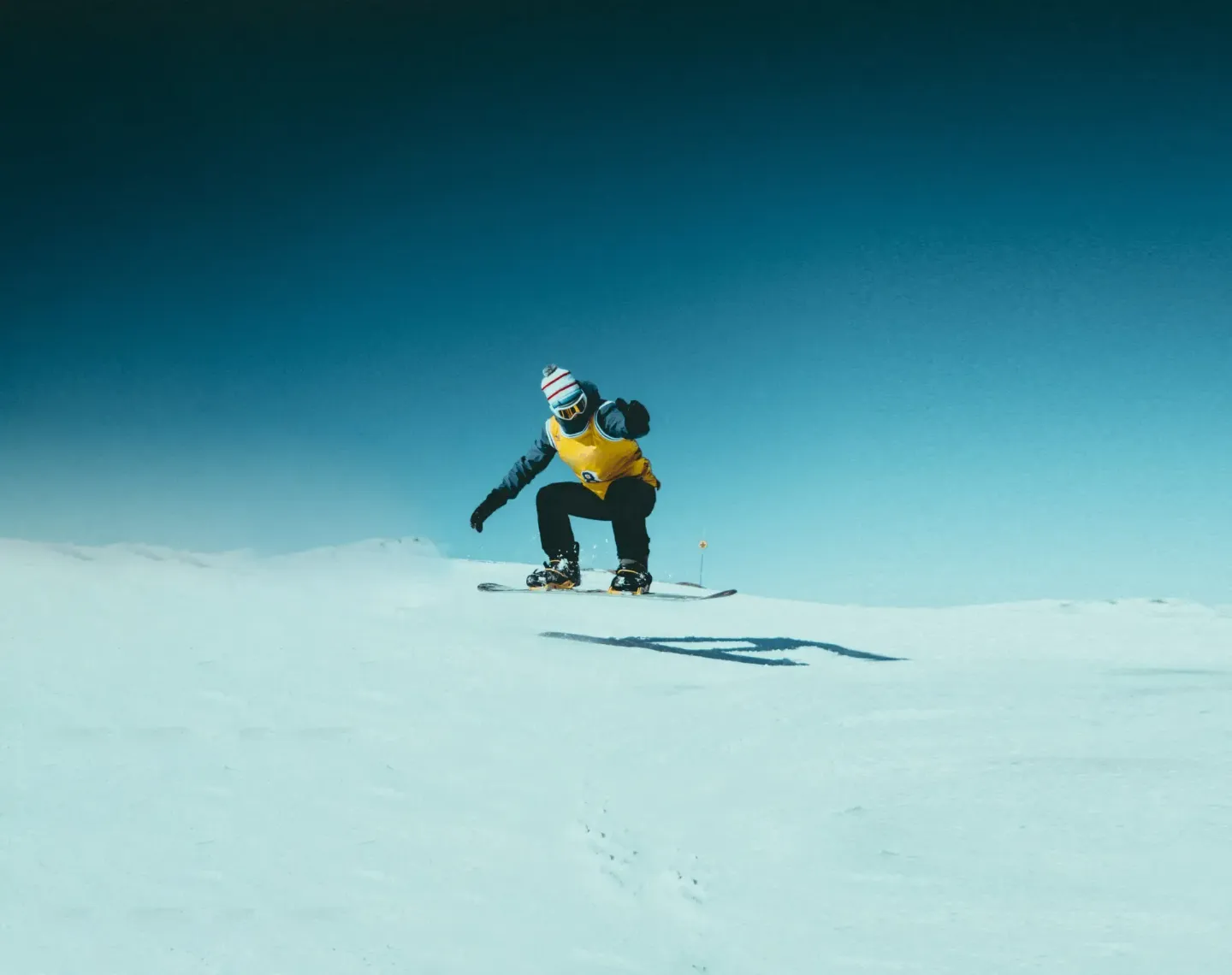 Individuo practicando el activo deporte de snowboard en la nieve, protegido en modo 24/7 por el Seguro de Accidentes Allianz Murcia, que cubre rescates y lesiones en la vida privada y laboral.