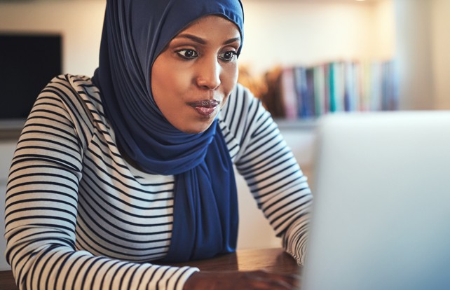 Female student wearing a head scarf and using a laptop computer