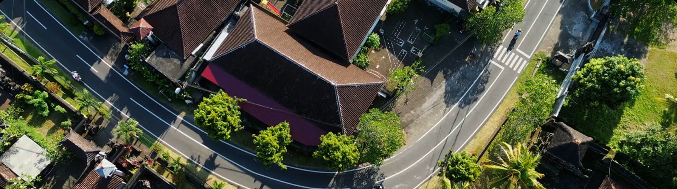 An aerial view of a tranquil, surburan neighborhood. A delivery drone flies diagonally across the homes.
