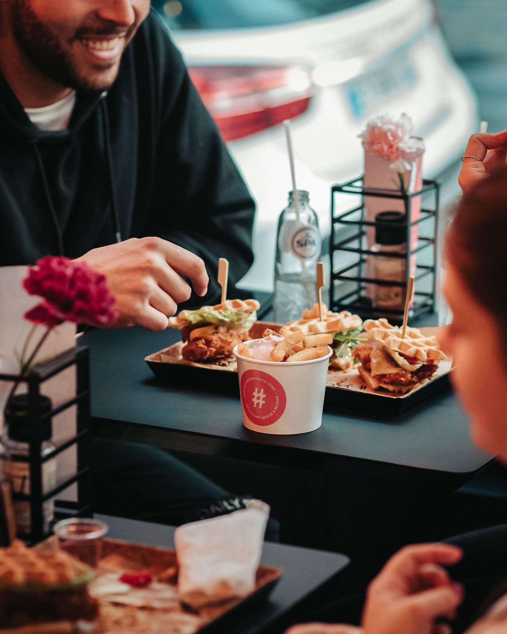 Modern home office setup with a monitor, ergonomic chair, keyboard, and indoor plants near a window with blinds.