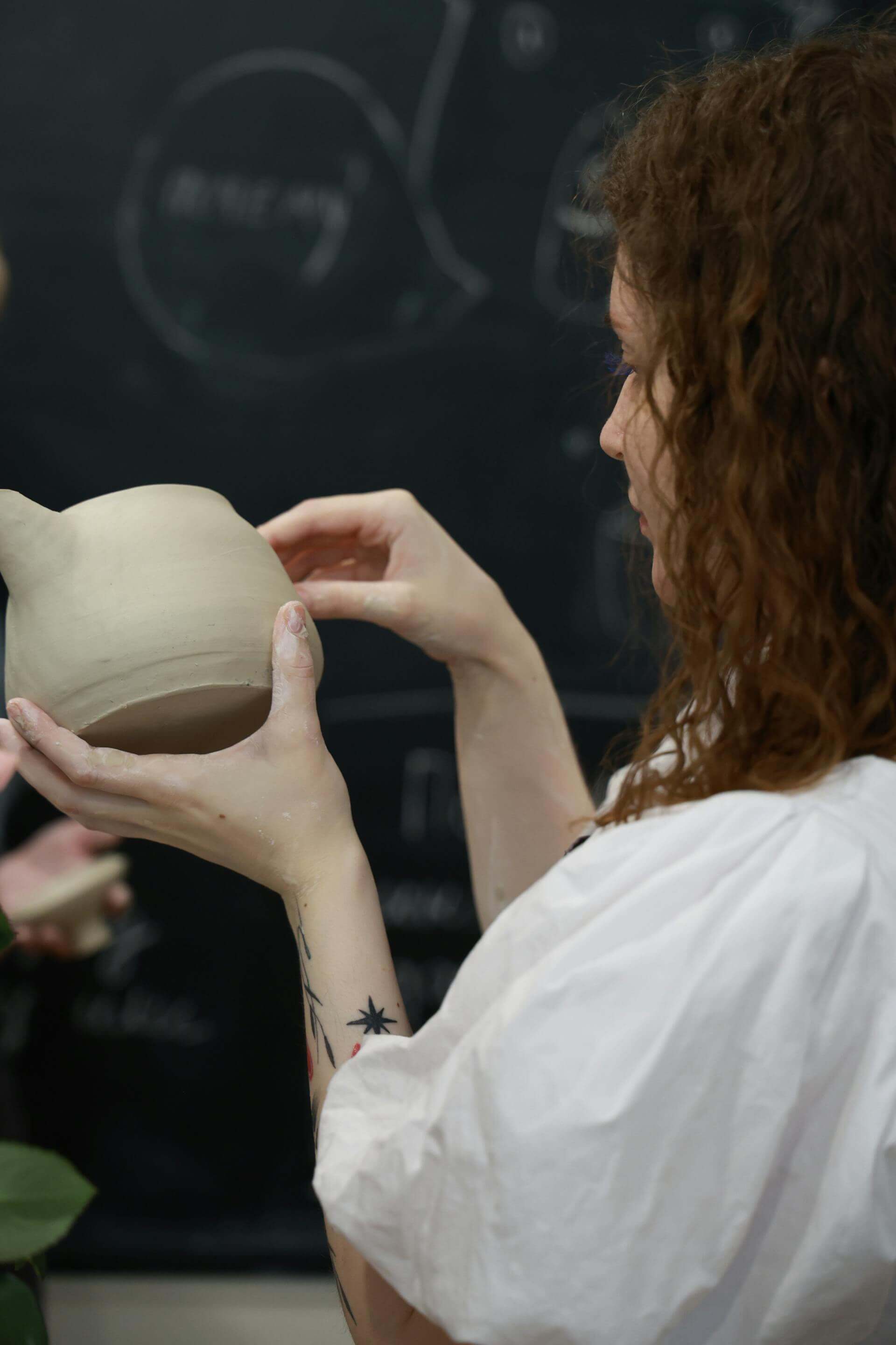 A woman gently cradles a beautifully crafted pottery vase in her hands, showcasing her appreciation for art