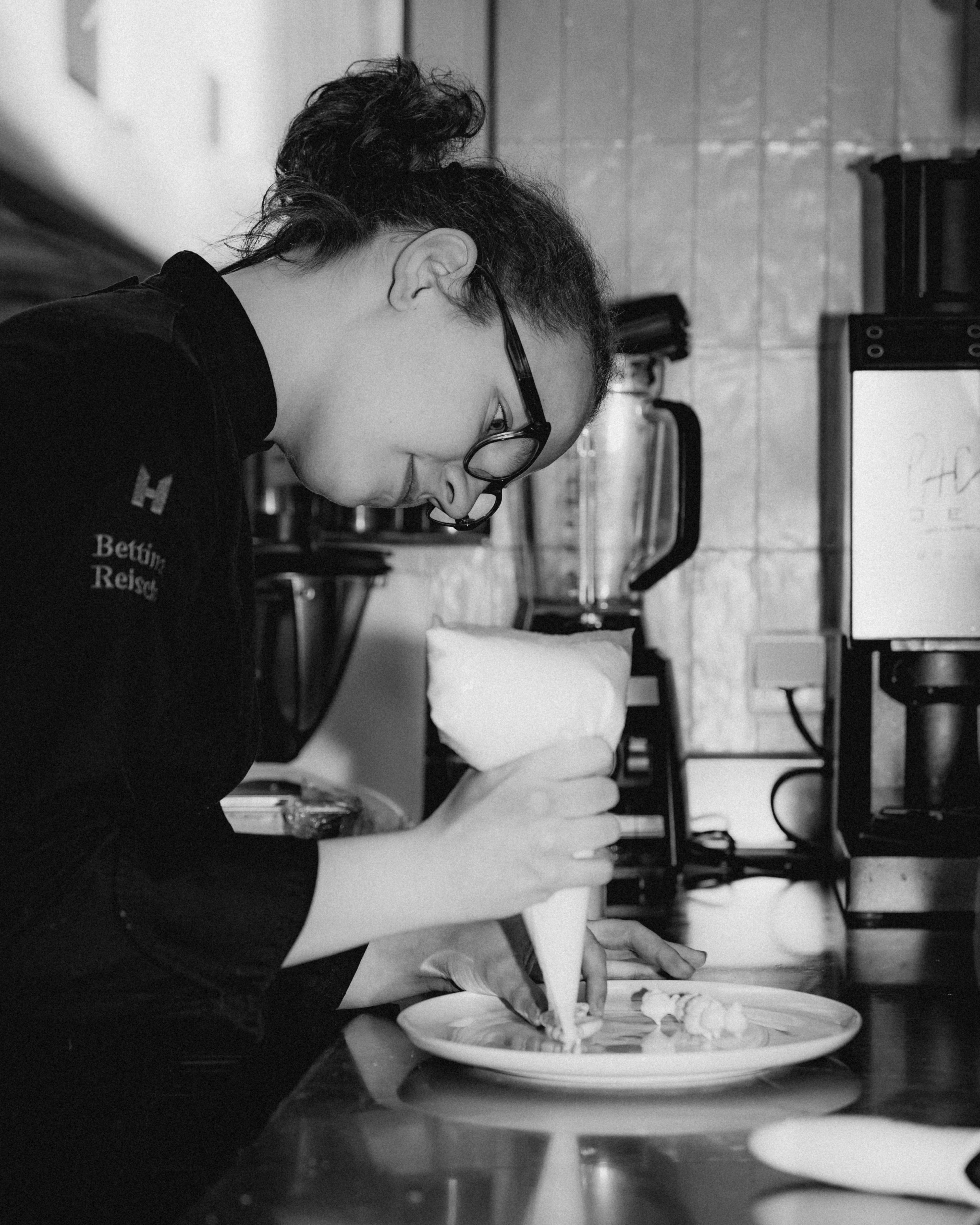 A black-and-white photo of a couple smiling at a bar with bottles in the background.