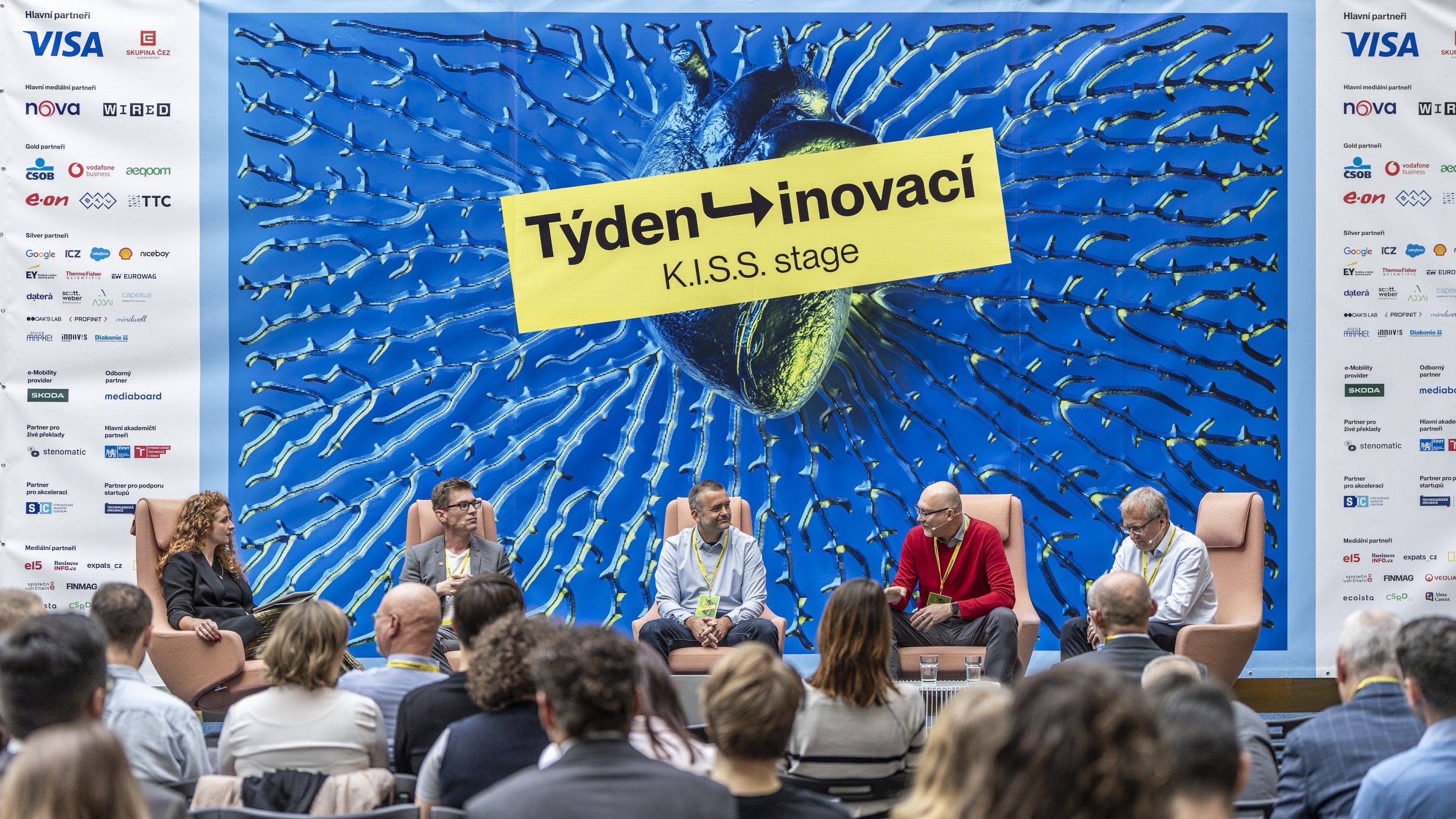 Panel discussion at a business conference with four speakers on stage in front of a “Týden inovací – K.I.S.S. stage” backdrop, audience seated in the foreground.