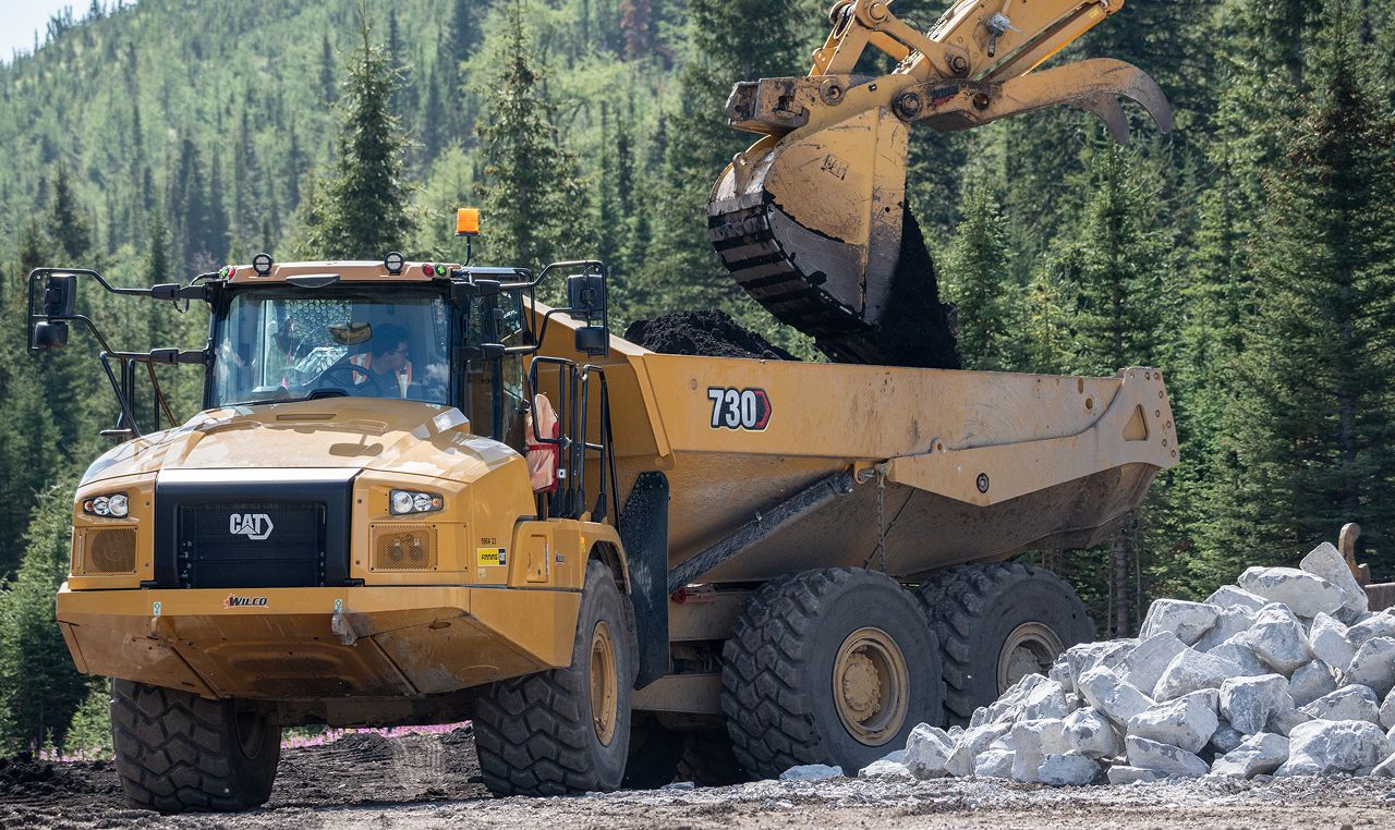 Articulated dump truck hauling material during Highwood Meadows parking lot construction in Kananaskis