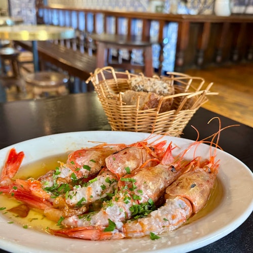 Gambas al ajillo (škampi s češnjakom) posluženi u maslinovom ulju uz hrskavi kruh u ambijentu madridskog restorana s vintage keramičkim pločicama.