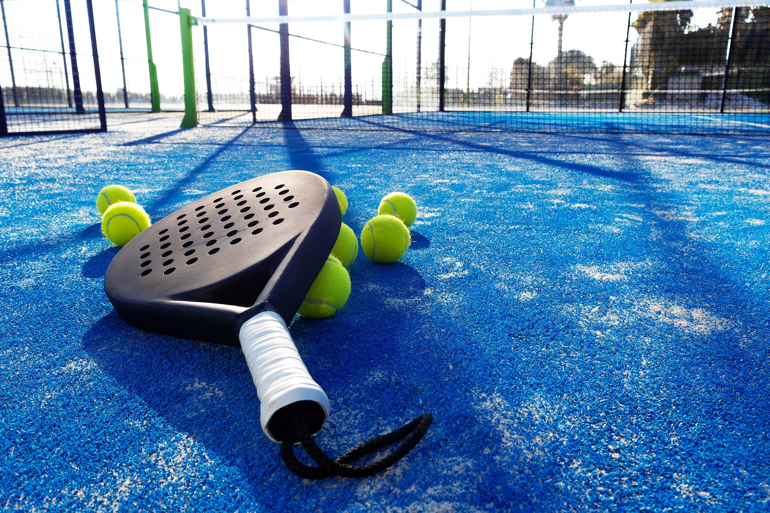 padel racket on the ground with padel ball under it