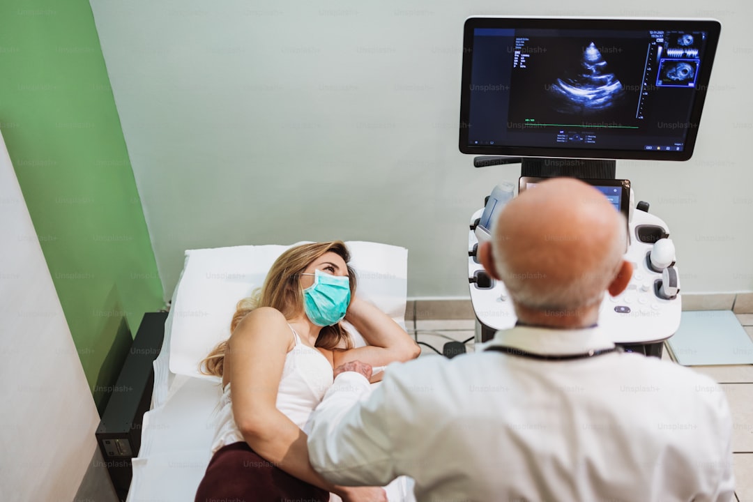 Femme masquée recevant une échographie cardiaque par un médecin.