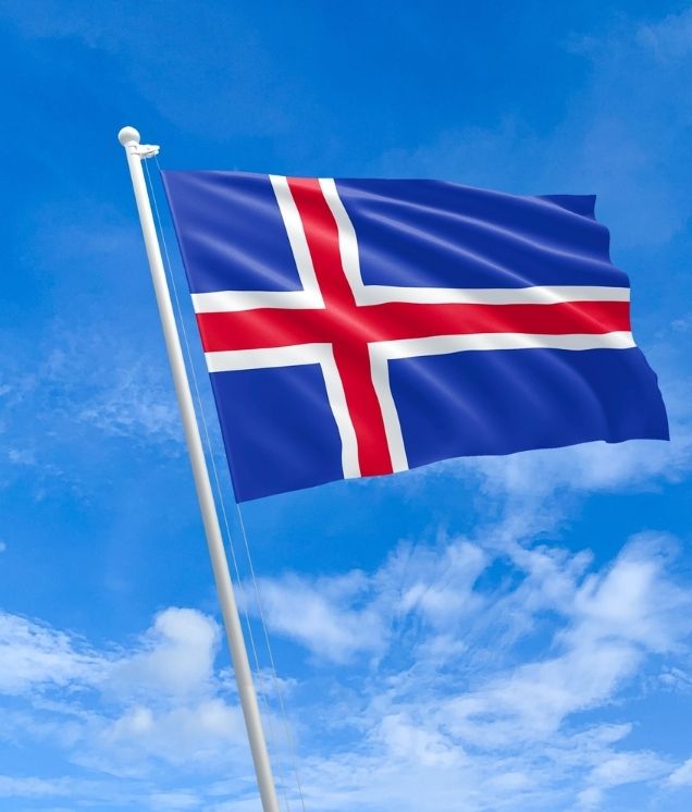 Icelandic flag fluttering in the wind against a blue sky.