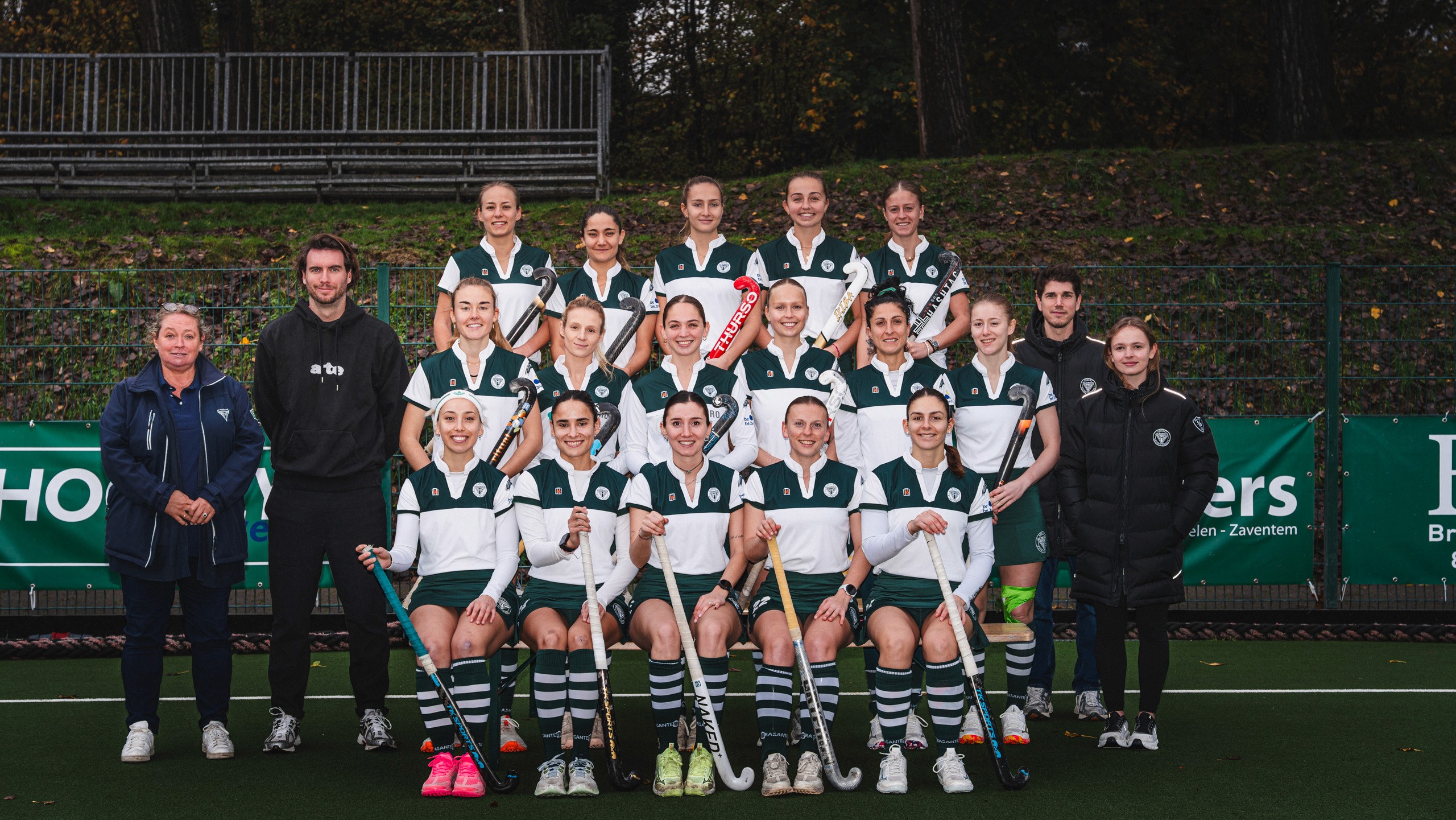 Three models standing in a wheat field, wearing beige suits.