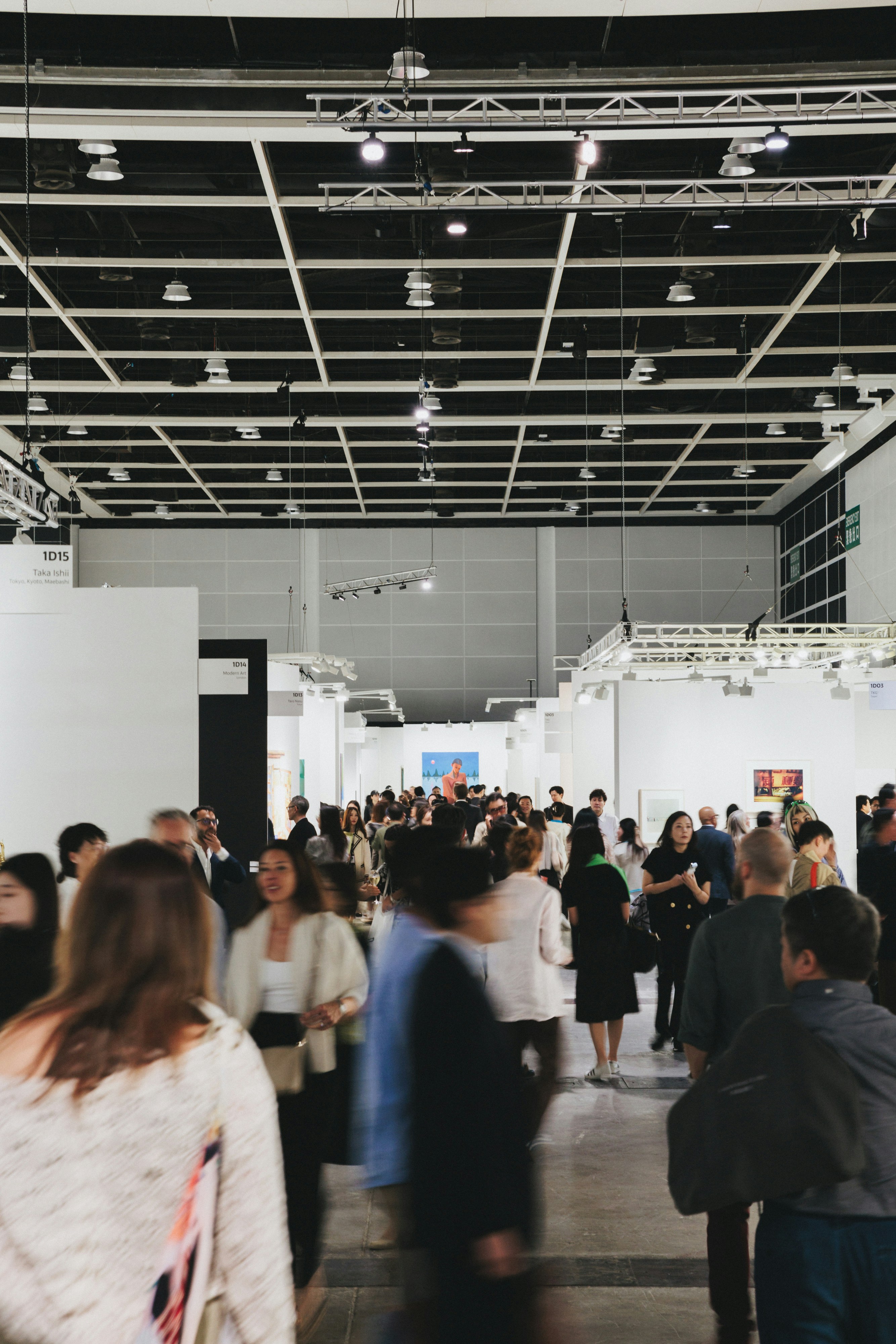 People browse art in a busy, modern gallery.