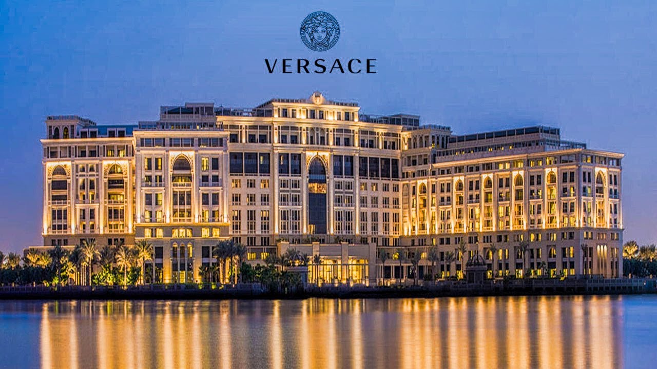 Minimal wooden table lamp with a curved frame and glowing round bulb on a light gray background.