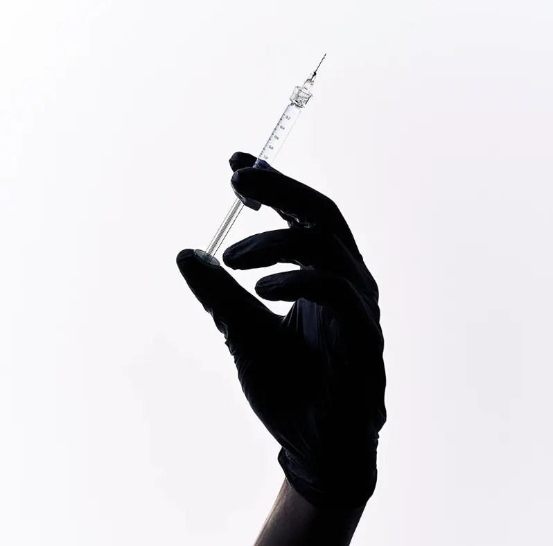 Silhouetted gloved hands holding a syringe and vial on a white background for medical device commercialization process.