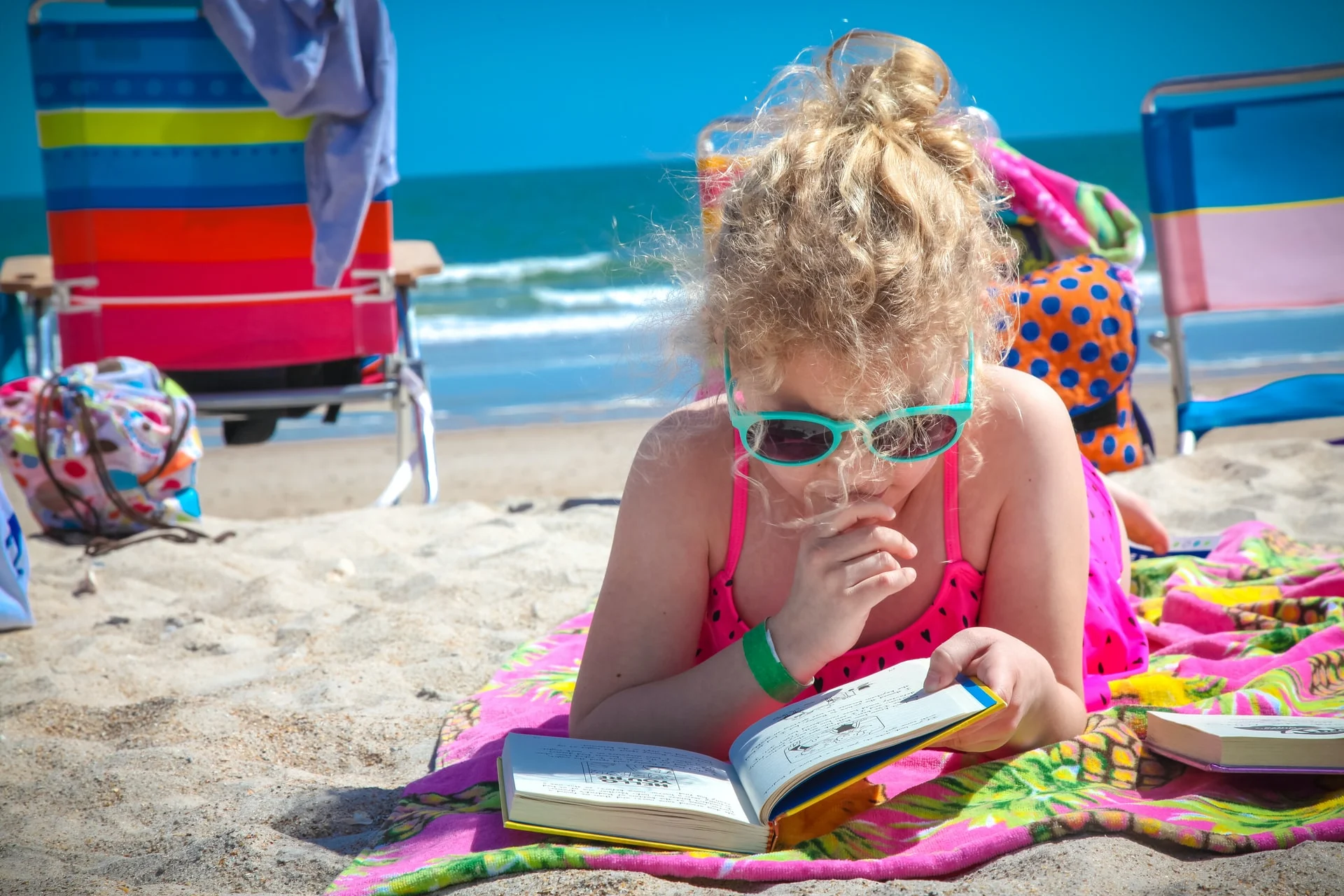 Child at the beach reading a book