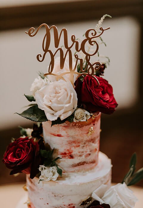 A beautifully decorated wedding cake featuring red and white roses.