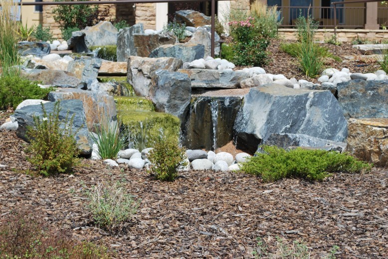 large flat rock boulders with water flowing in the backyard landscape design of an upscale home in castle rock, colorado