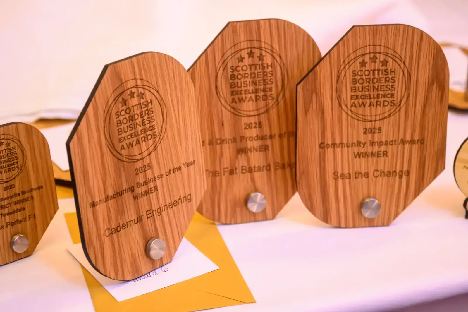 Wooden plaques with engraved text from the Scottish Borders Business Excellence Awards 2025 are displayed, exuding a sense of achievement and recognition.