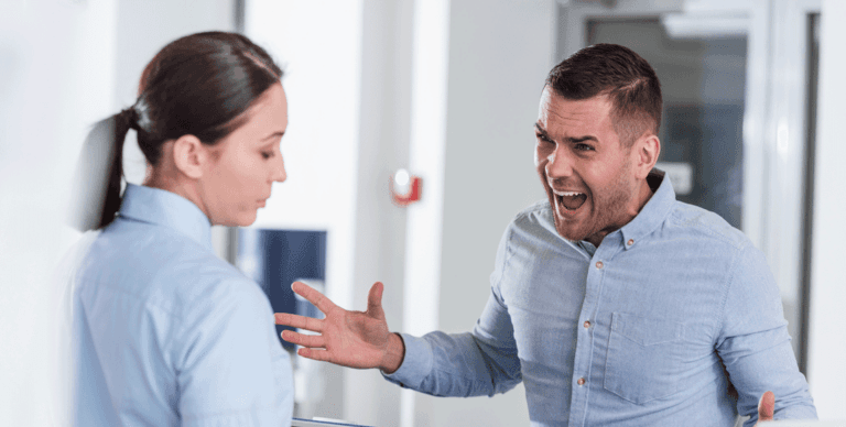 Man shouting angrily at a woman in a workplace setting.