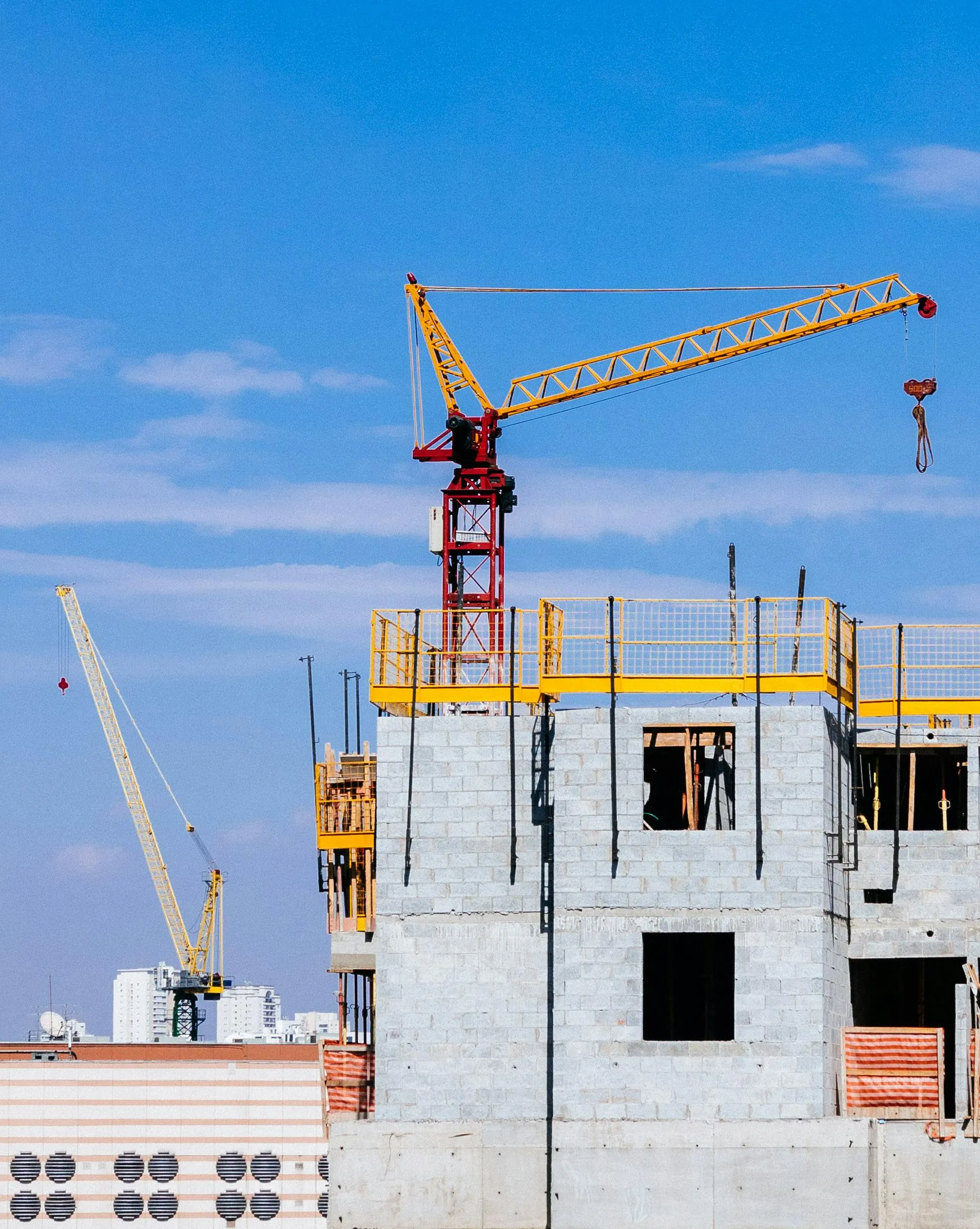 Construction worker wearing a hardhat and safety vest reviewing architectural blueprints on-site.