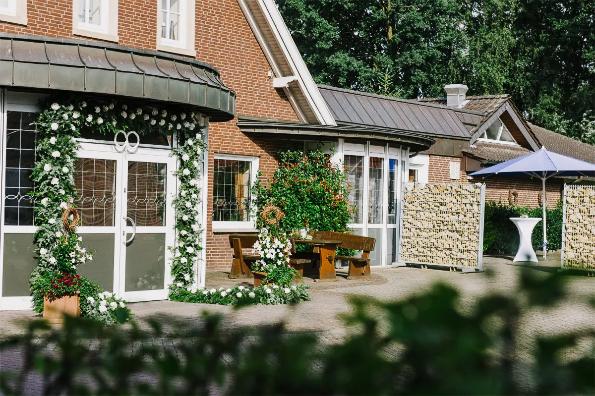 Haus mit Blumenschmuck an den Türen. Holzbank und Tisch im Freien für Veranstaltungen.