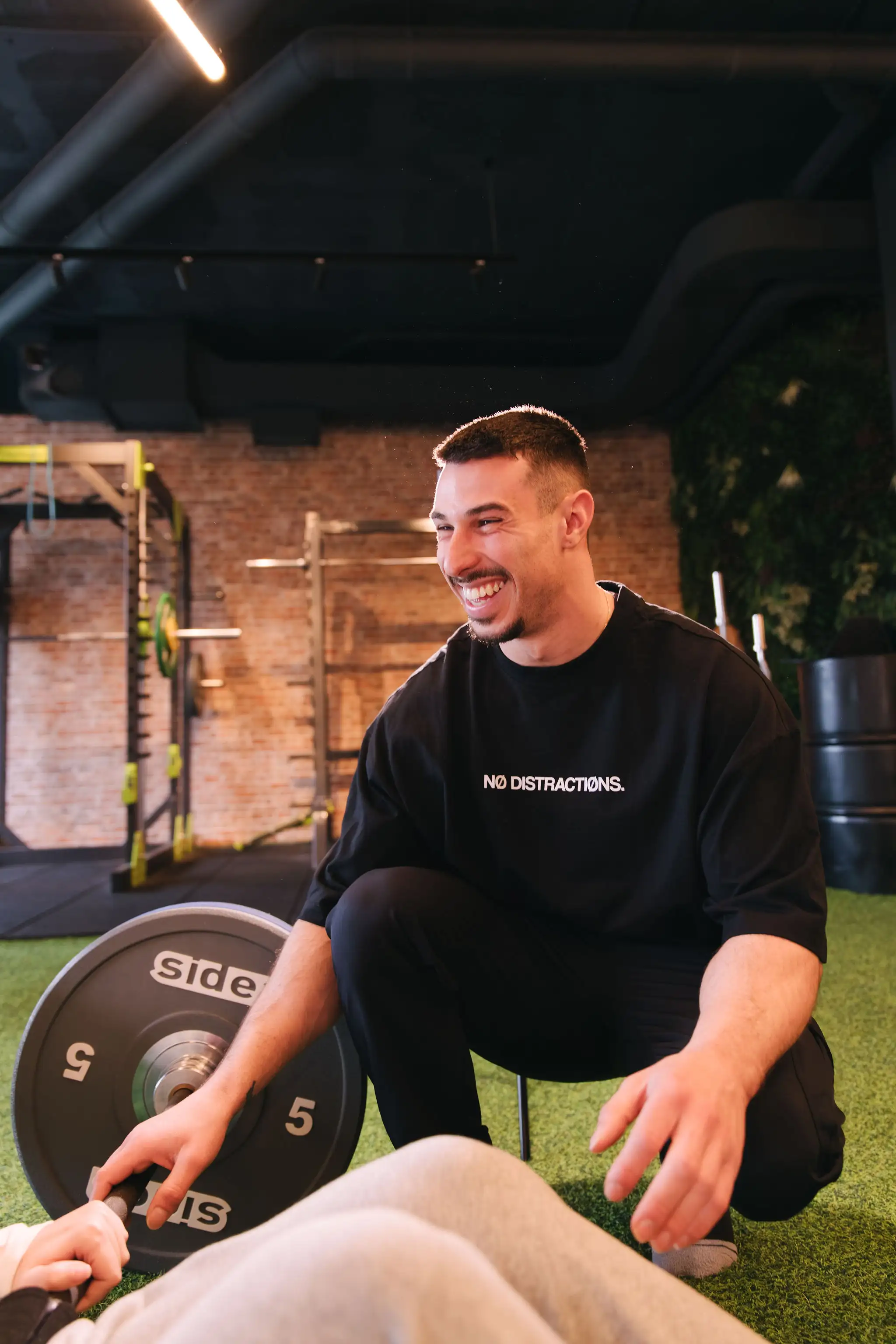 Entrenador corrigiendo técnica de entrenamiento a clienta en La Base Strength, Sitges