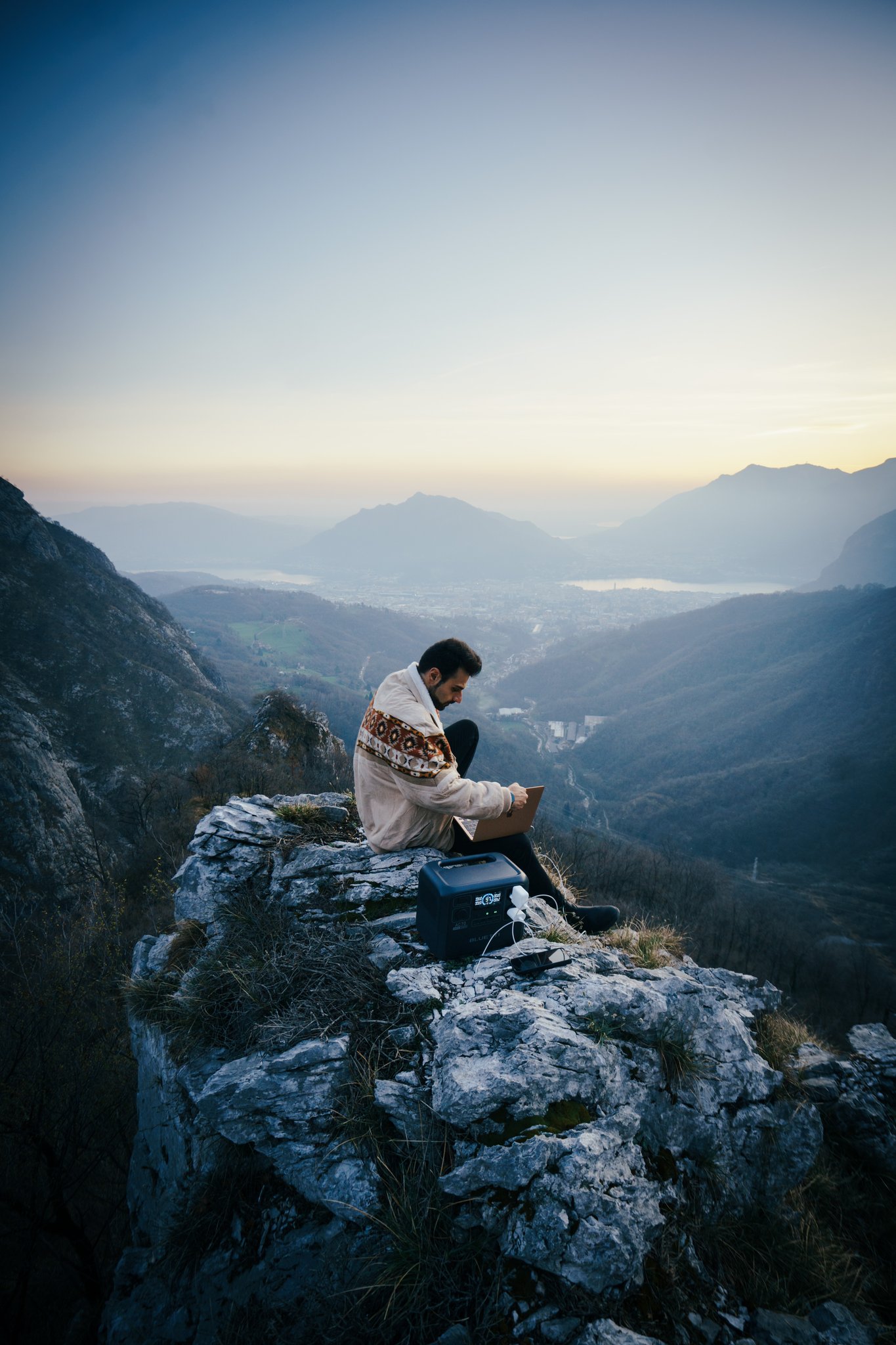 A film director sits in a chair facing a bustling, warmly lit night market scene. A camera setup is nearby, capturing the energetic atmosphere.