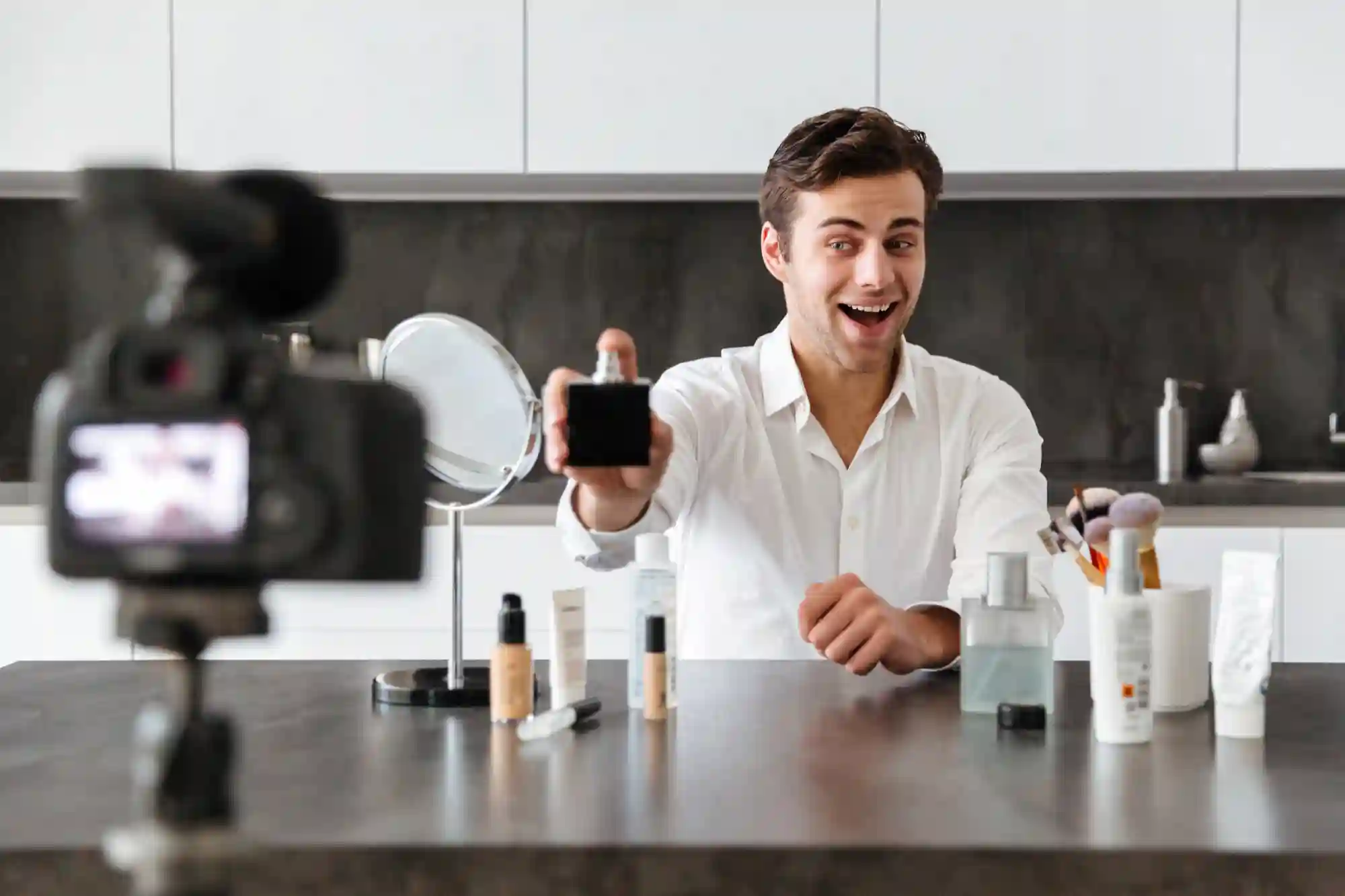 Enthusiastic male beauty influencer reviewing men's skincare or fragrance products while recording a video.