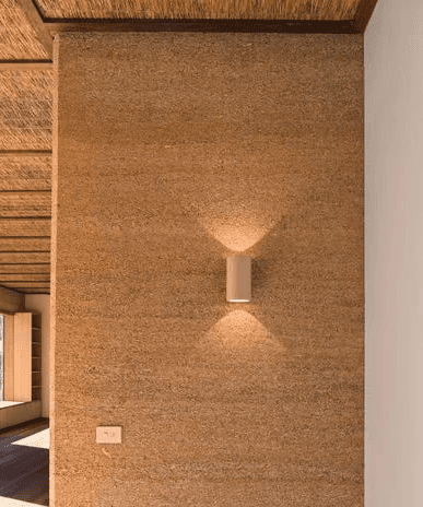 A beautiful photo of a lamp attached to a hempcrete wall.