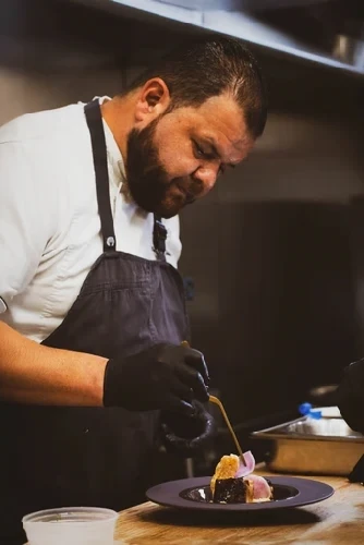 Chef in black uniform working at a kitchen preparation station